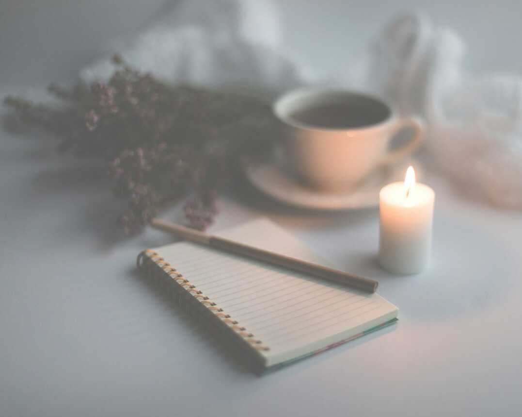 Open notebook with handwriting and a cup of coffee on a wooden desk