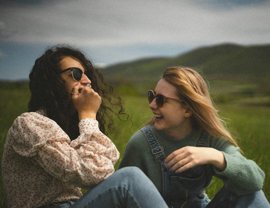 Two women having a warm conversation, sitting close with genuine smiles